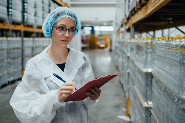 Tıbbi malzeme araştırma ve üretim fabrikasında çalışan ve sevkiyattan önce damıtılmış su dolu kutuları kontrol eden koruyucu işçi. Denetleme kalite kontrolü. Sanayi deposu.