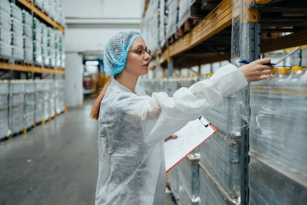 Tıbbi malzeme araştırma ve üretim fabrikasında çalışan ve sevkiyattan önce damıtılmış su dolu kutuları kontrol eden koruyucu işçi. Denetleme kalite kontrolü. Sanayi deposu.