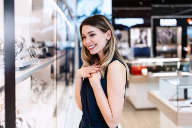 Muhteşem genç bayan pahalı kuyumcuda eğleniyor. Moda tarzı ve zarafet konsepti.