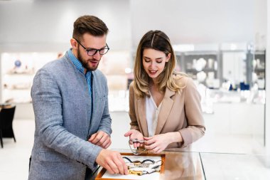 Zarif orta yaşlı işadamı yeni pahalı saatini seçip alıyor. Güzel genç bayan satıcı doğru karar vermesine yardımcı oluyor. Moda tarzı ve zarafet konsepti.