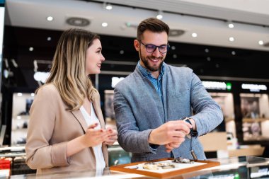 Zarif orta yaşlı işadamı yeni pahalı saatini seçip alıyor. Güzel genç bayan satıcı doğru karar vermesine yardımcı oluyor. Moda tarzı ve zarafet konsepti.