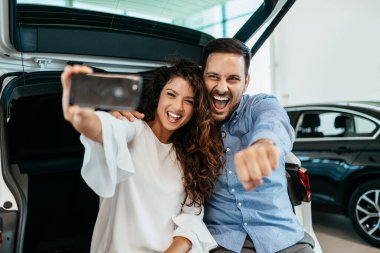 Mutlu orta yaşlı çift galeride yeni araba seçerken ve alırken eğleniyor..