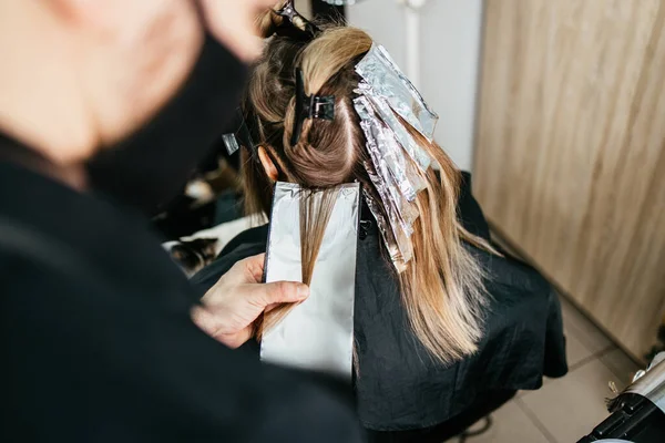 理发师正在给女性的头发染色 用锡箔给他的客户做发亮 — 图库照片