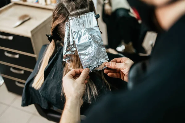 美容師は女性の髪を染め 箔で彼のクライアントに髪のハイライトを作ります — ストック写真