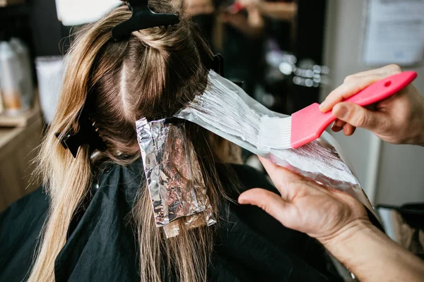 美容師は女性の髪を染め 箔で彼のクライアントに髪のハイライトを作ります — ストック写真