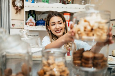 Pastanede ya da pastanede çalışan genç ve güzel bir bayan satıcı. Lezzetli tatlılar satıyor ve paketliyor..
