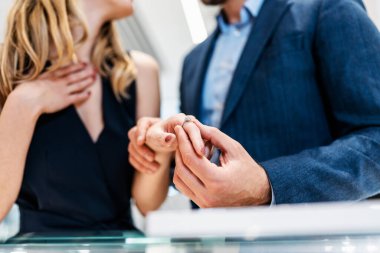 Modern kuyumcuda alışveriş yapan güzel bir çift. Pahalı bir yüzük ve bilezik takmış bir kadının elini yakın plan çek..