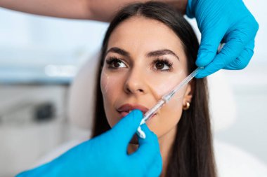 Güzel esmer kadın hasta botulinyum toksin iğneleri ya da hyaluronik asit doldurucu ile tıbbi ve güzellik tedavisine hazırlanıyor..