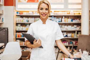 Bir eczanede çalışan genç ve çekici bir kadın eczacı. Mutlu ve gülümsüyor..