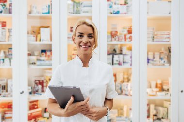 Bir eczanede çalışan genç ve çekici bir kadın eczacı. Mutlu ve gülümsüyor..