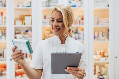 Bir eczanede çalışan genç ve çekici bir kadın eczacı. Mutlu ve gülümsüyor..