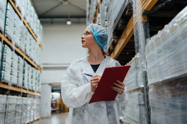 Tıbbi malzeme araştırma ve üretim fabrikasında çalışan ve sevkiyattan önce damıtılmış su dolu kutuları kontrol eden koruyucu işçi. Denetleme kalite kontrolü. Sanayi deposu.