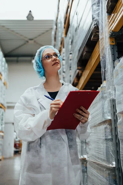 在医疗用品研究和生产工厂工作的从事保护工作的女工在装运前检查瓶装蒸馏水 检查质量控制 工业仓库 — 图库照片