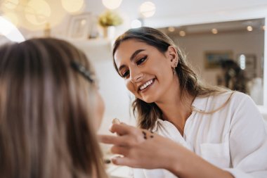 Makyaj süreci. Makyaj için makyaj yapan profesyonel bir sanatçı. Güzellik uzmanının yüzüne odaklan. Parlak ışıklı güzellik salonu.. 