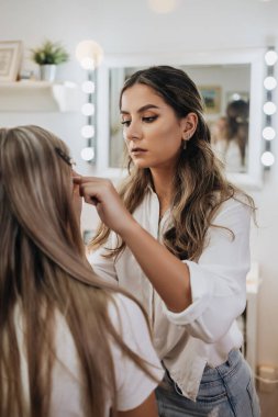Makyaj süreci. Makyaj için makyaj yapan profesyonel bir sanatçı. Güzellik salonundaki güzel sarışın kadının portresini yakından çek..