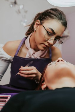 Kirpik uzatma prosedüründeki güzel kızıl saçlı kadın. Kozmetik ve vücut bakımı yakın çekim. Sığ alan derinliği ve seçici odak.