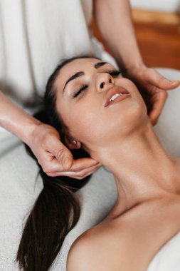 Güzel genç bir kadın aromaterapi ile profesyonel vücut masajı yaptırıyor..