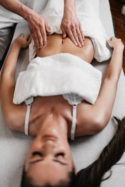 Güzel genç bir kadın aromaterapi ile profesyonel vücut masajı yaptırıyor..