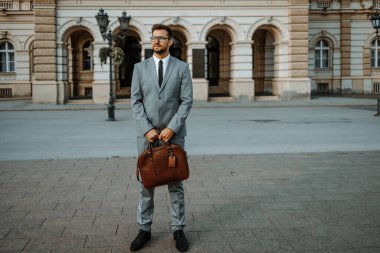 Şehir caddesinde duran yakışıklı orta yaşlı iş adamının portresi. Kendinden emin ve ciddi. Sinematik renk notu.