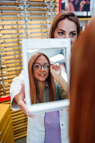Beautiful Fashionable Redhead Woman Choosing Eyeglasses Frame Modern Optical Store — стоковое фото