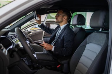 Galeride çalışan araba satıcısı ve araba detaylarını son kez kontrol ediyor alıcı gelmeden önce..