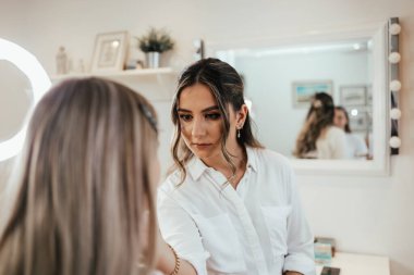 Makyaj süreci. Makyaj için makyaj yapan profesyonel bir sanatçı. Güzellik salonundaki güzel sarışın kadının portresini yakından çek..