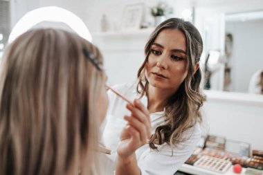 Makyaj süreci. Makyaj için makyaj yapan profesyonel bir sanatçı. Güzellik salonundaki güzel sarışın kadının portresini yakından çek..