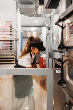Modern bir fırında ya da fast food restoranında çalışan genç ve güzel bir bayan işçi..
