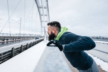 Çok soğuk ve karlı bir günde sakallı, koşan ve dışarıda egzersiz yapan yakışıklı orta yaşlı bir adam. Spor ve spor motivasyon teması.
