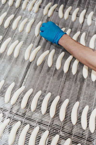 Huge factory line for sweet food and cookies production. Close up shots of worker\'s hand with protective glove doing some selection and product arranging.