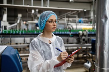 Tıbbi malzeme araştırma ve üretim fabrikasında çalışan ve sevkiyattan önce damıtılmış su kutularını kontrol eden koruyucu işçi. Denetim kalite denetimi. 