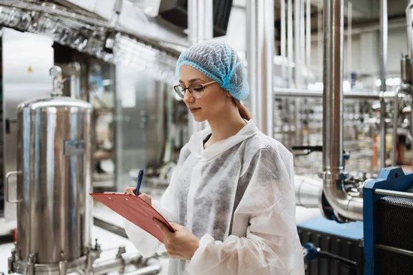 在医疗用品研究和生产工厂工作的从事保护工作的女工在装运前检查蒸馏水罐 检查质量控制 — 图库照片