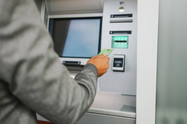 Şehir caddesinde gözlüklü yakışıklı orta yaşlı bir işadamı kredi kartı veya banka kartından para çekmek için ATM kullanıyor. Eller yukarı..