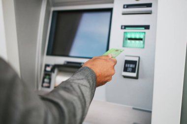 Şehir caddesinde gözlüklü yakışıklı orta yaşlı bir işadamı kredi kartı veya banka kartından para çekmek için ATM kullanıyor. Eller yukarı..