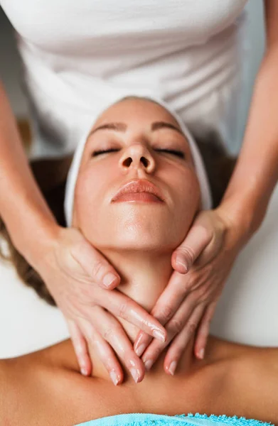 Body and neck massage in spa. Professional female beautician doctor with patient in wellness center. Cosmetologist working procedure to beautiful young adult woman in cosmetology cabinet or beauty parlor. Close up shot.