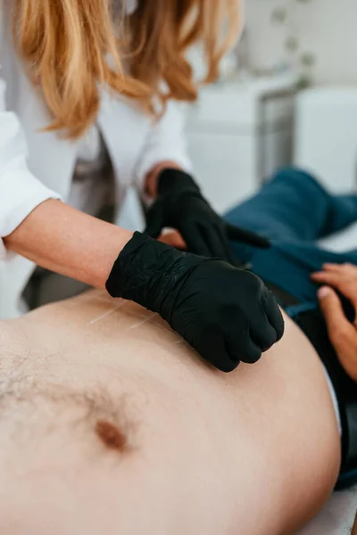 Handsome middle age man receiving advanced stomach fat burning lipolysis treatment. Modern aesthetics treatments for males. Healthcare and beauty concept.