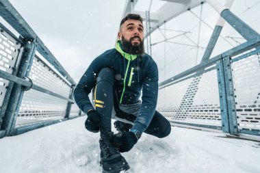 Çok soğuk ve karlı bir günde sakallı, koşan ve dışarıda egzersiz yapan yakışıklı orta yaşlı bir adam. Spor ve spor motivasyon teması.