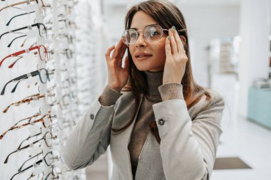 Modern optik mağazada gözlük çerçevesi seçen güzel ve şık bir kadın..