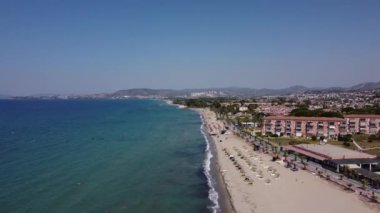 Güneşli bir günde güzel bir sahil sahilinde yüzen ve güneşlenen insanların hava görüntüsü