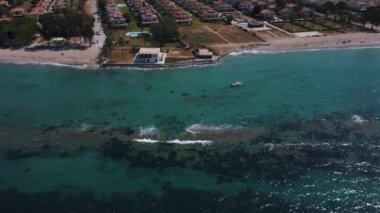 Yeşil Renkli Deniz manzaralı Tarifler ve balıkçı teknesi ve arka planda yüzme havuzları olan Triplex Villaları olan bir Sahil Konağı