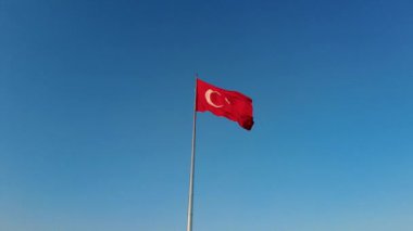 Yerin üstünde bayrak direğinde dalgalanan büyük bir Türkiye bayrağı.