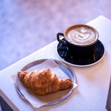 Sıcak kahve ve kruvasan mermer bir tablo