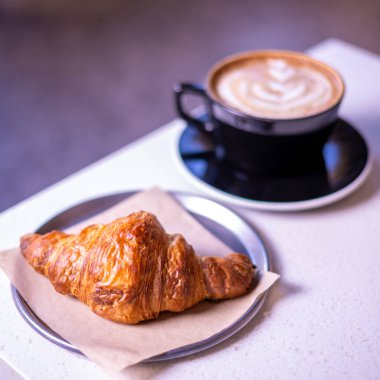 Sıcak kahve ve kruvasan mermer bir tablo