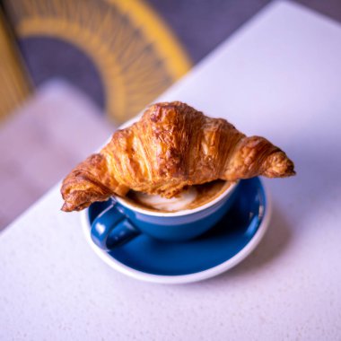 Croissant on cup of coffee. Marble backgroun