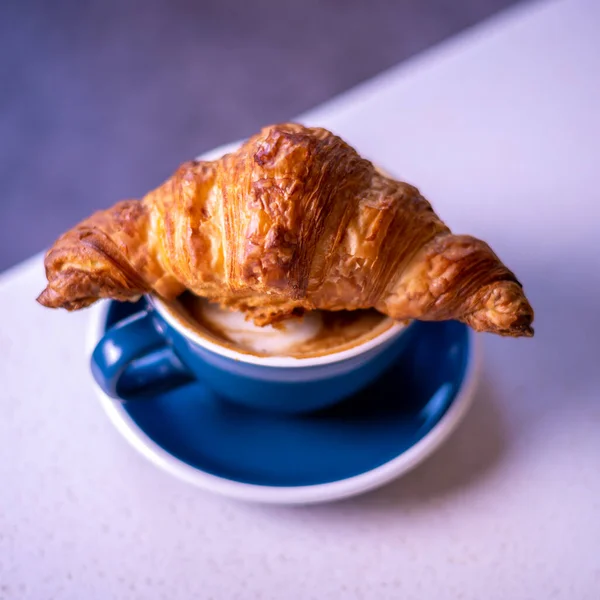 Croissant on cup of coffee. Marble backgroun