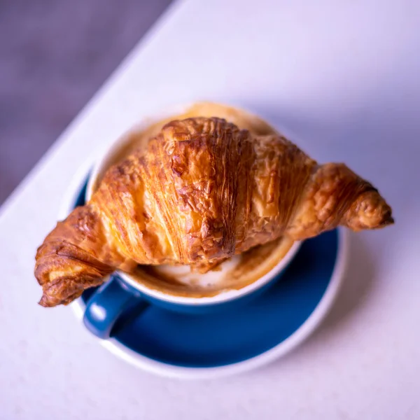 Croissant on cup of coffee. Marble backgroun