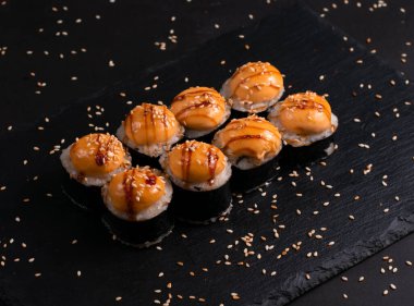 Set of baked sushi rolls on a black background. Japanese oriental cuisin