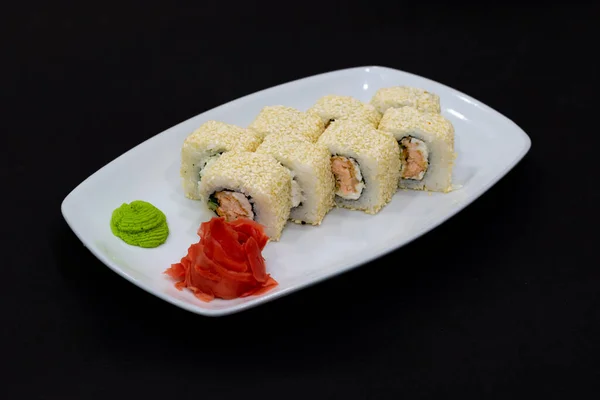 Alaska roll on black. Alaska roll on a plate with ginger and wasabi
