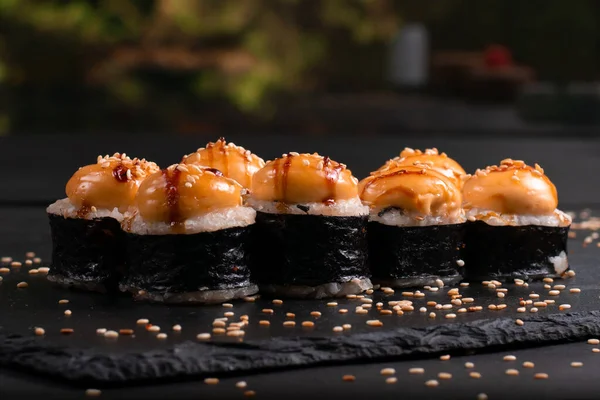 Set of baked sushi rolls on a black background. Japanese oriental cuisin