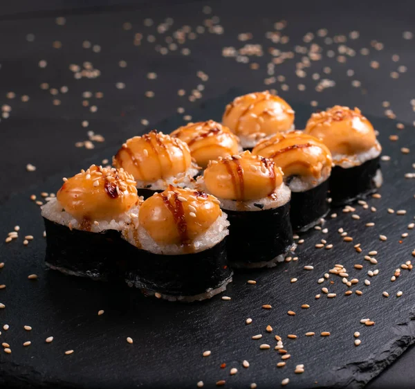 Set of baked sushi rolls on a black background. Japanese oriental cuisin